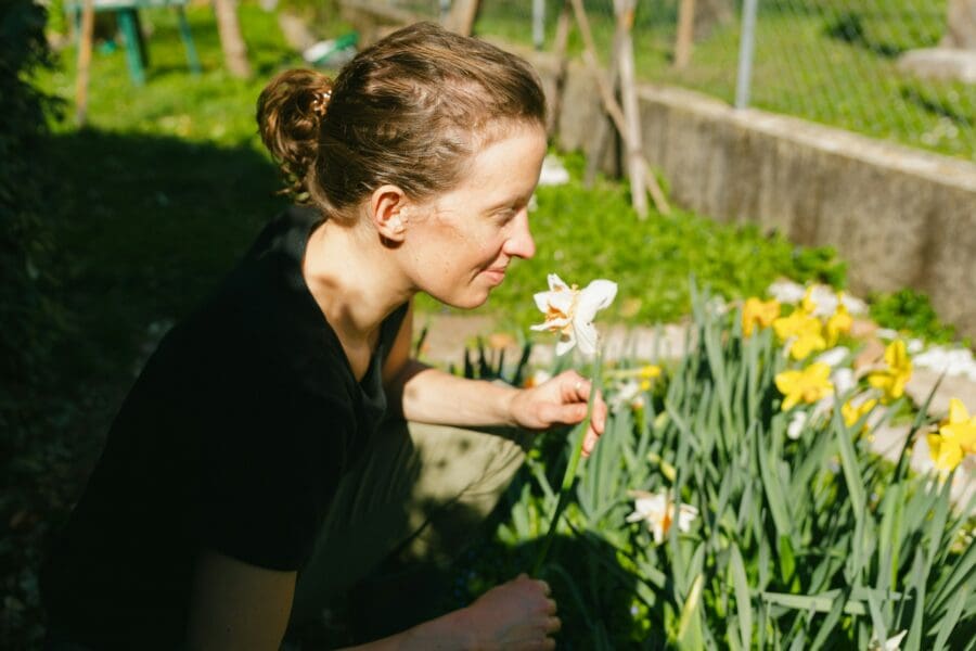 A woman tenderly caring for daffodils in a sunlit memorial garden, created to honor a loved one and alleviate her feelings of guilt while grieving