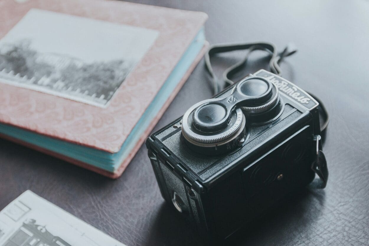 Vintage camera and photo album representing the transition from physical keepsakes to digital memories, as we shift to digital formats to preserve and share moments.